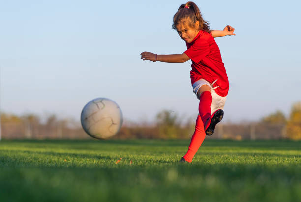 Girl kicks a soccer ball on a soccer field